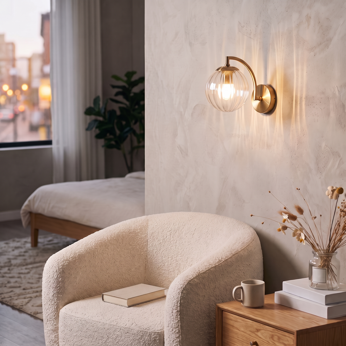 Curved Arm Ball Sconce in brass, lit beside a boucle armchair in a bedroom