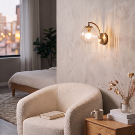 Curved Arm Ball Sconce in brass, lit beside a boucle armchair in a bedroom