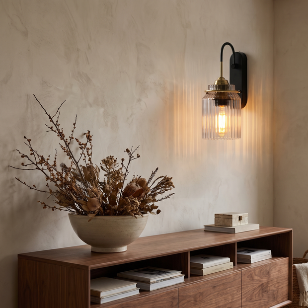 Gold wavy glass wall sconce above walnut console in living room