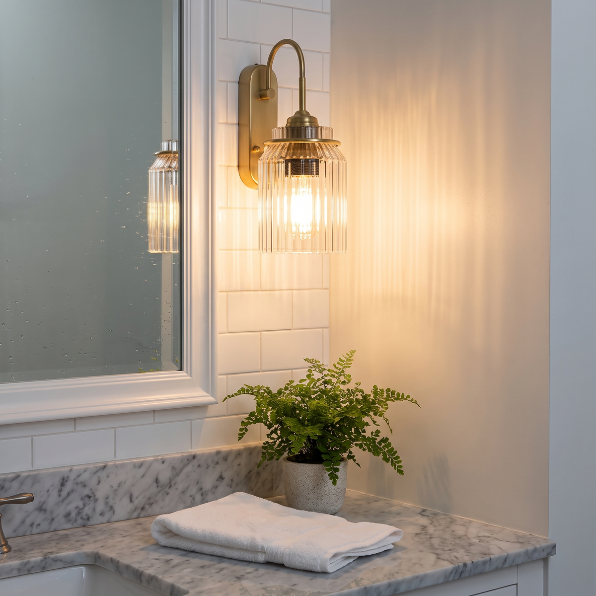 Gold wavy glass wall sconce beside bathroom vanity mirror