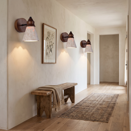 Three travertine wood sconces along a limewashed hallway