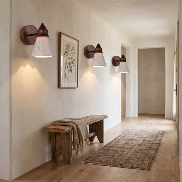Three travertine wood sconces along a limewashed hallway