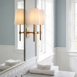 Rowan Linen Shade Brass Wall Lamp beside a bathroom mirror
