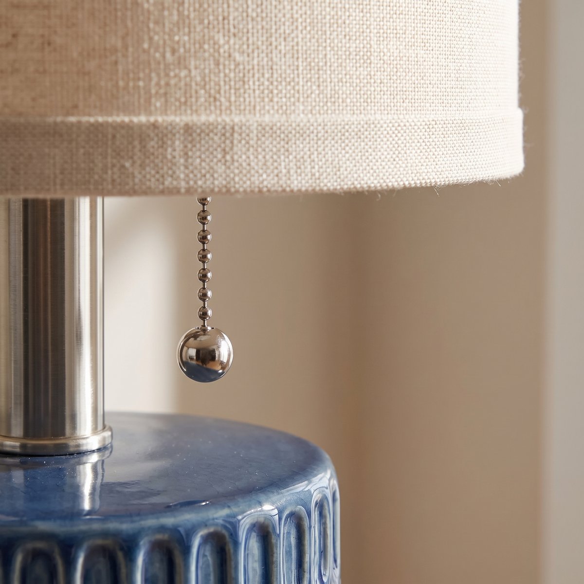 Close-up of the pull chain beneath the beige linen lamp shade