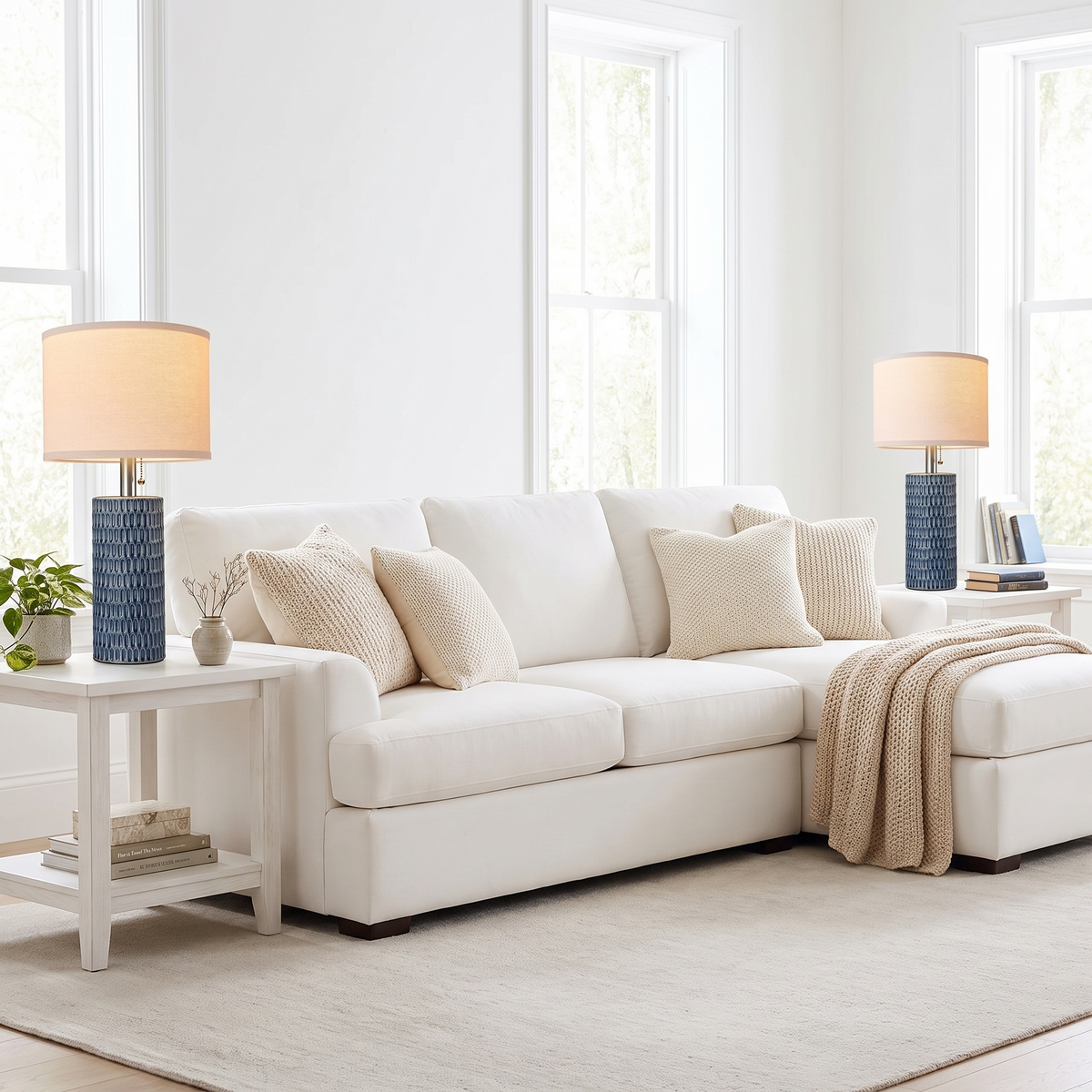 Blue ceramic lamps on end tables flanking a white sectional in a bright den