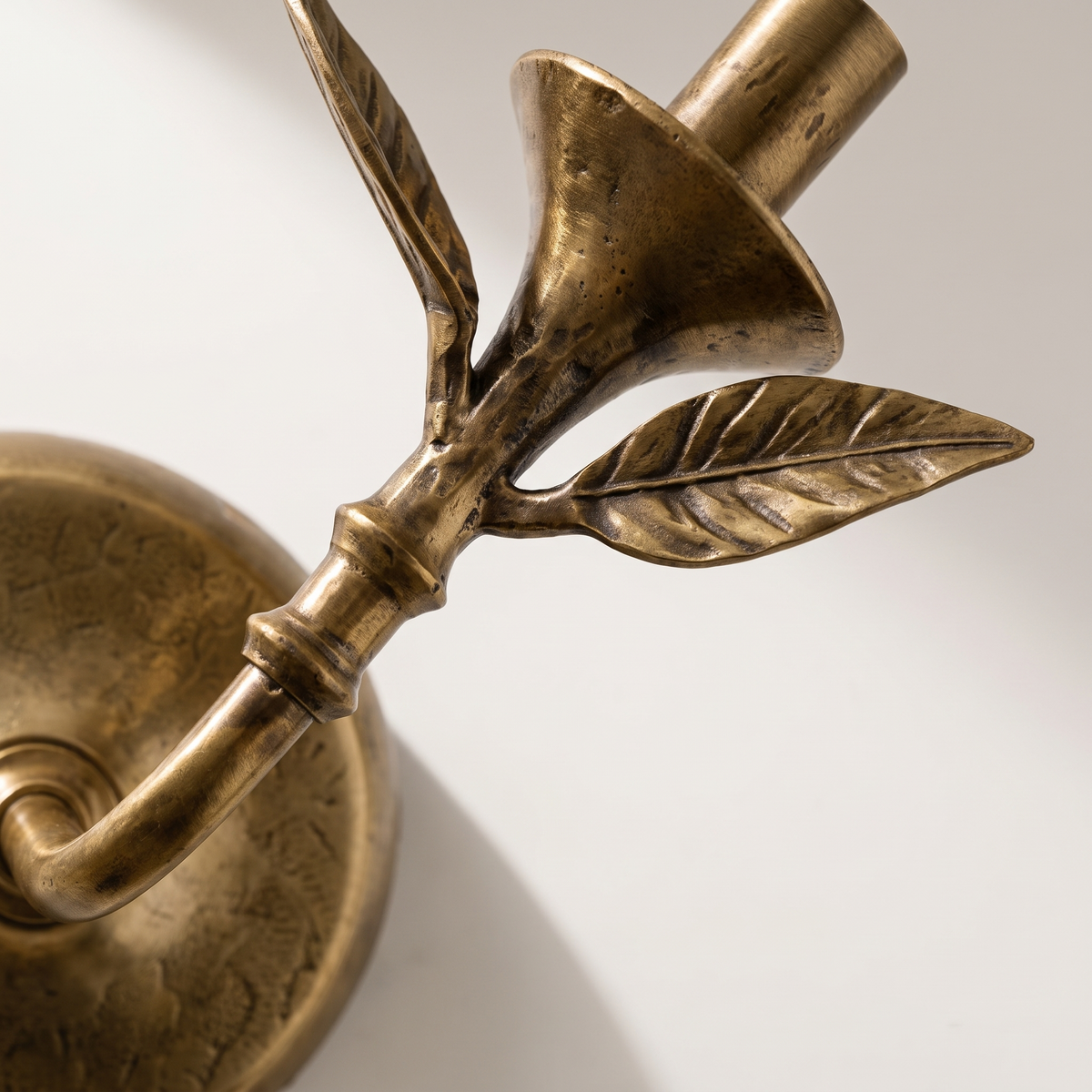 Close-up detail of the Roven sconce stem and sculpted botanical leaves