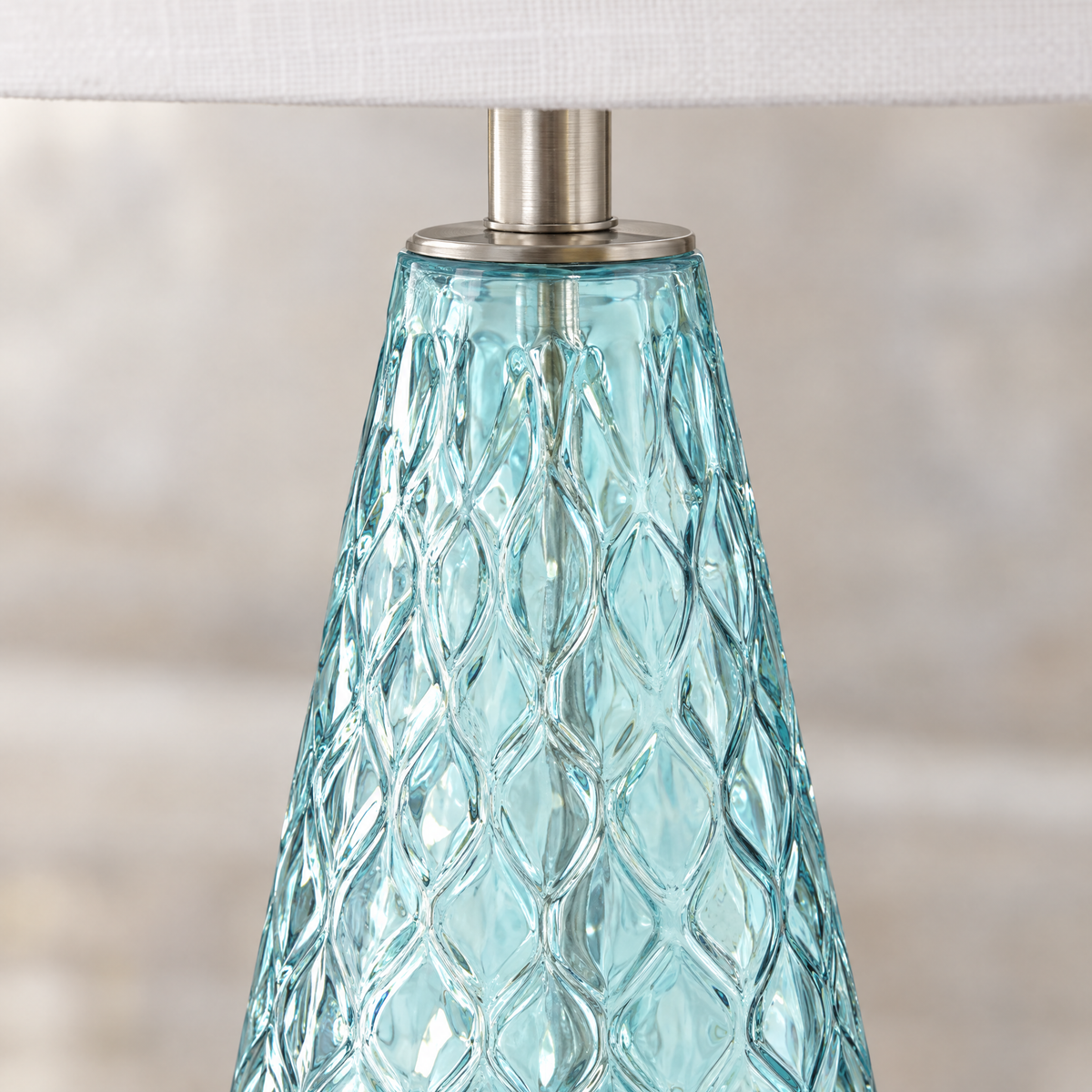 Close-up of textured diamond-pattern blue glass lamp base with brushed nickel fittings