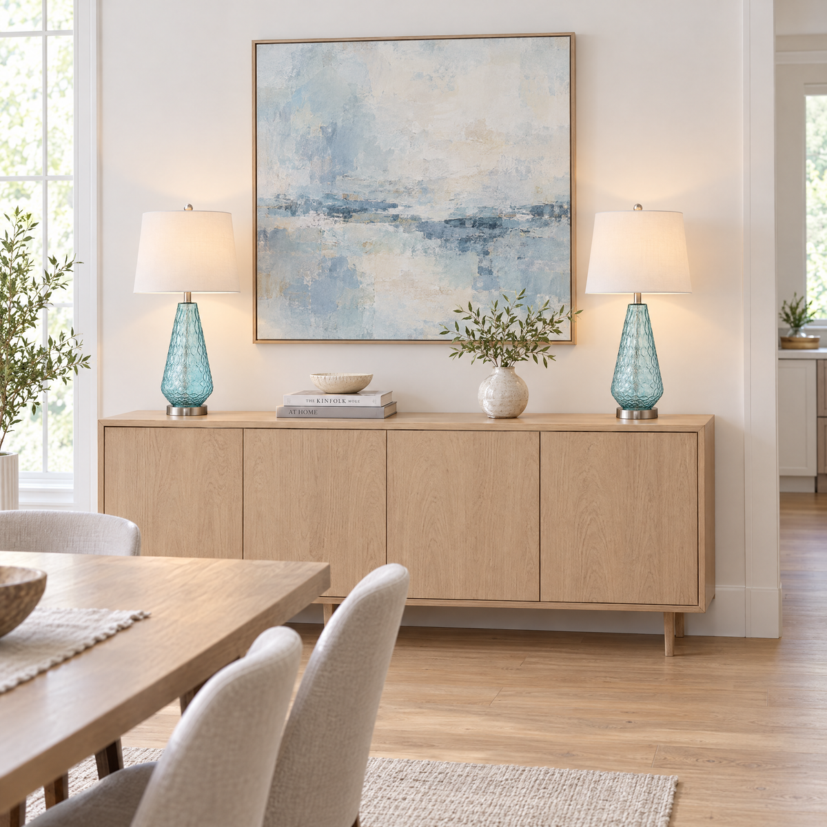 Pair of blue glass table lamps on a light oak sideboard in a modern dining room
