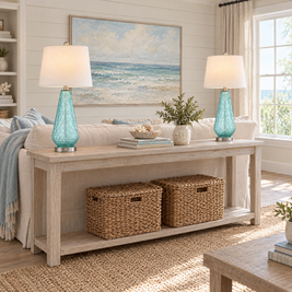 Pair of blue glass table lamps on a whitewashed sofa table in a coastal living room