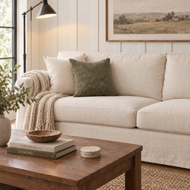 Dark sage jacquard pillow cover on a cream linen sofa in a modern farmhouse living room